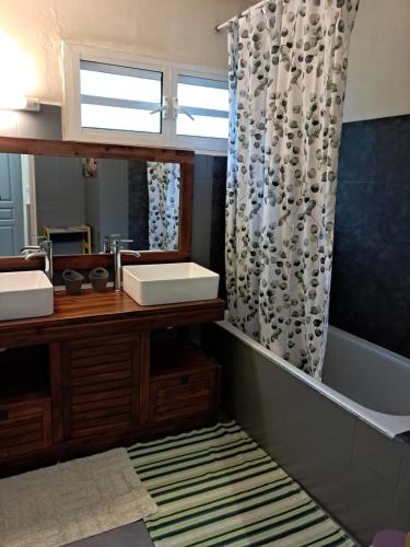 a bathroom with a sink and a shower curtain at Chambre d'hôte Les Amoureux du Cirque in Cilaos