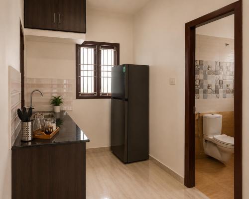 a kitchen with a black refrigerator and a toilet at Serene Padmanabham Premium Luxury Apartments Near Sree Padmanabhaswamy Temple in Trivandrum