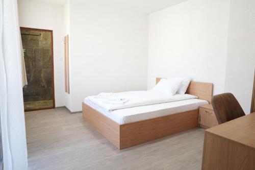 a bedroom with a bed with white sheets and a desk at Къща за гости Мекана in Borino