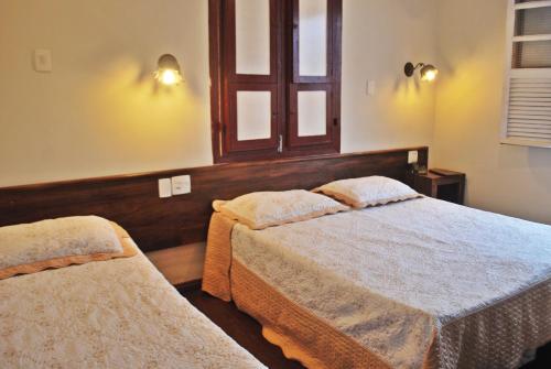 a bedroom with two beds and a window at Pousada dos Bandeirantes in Ouro Preto
