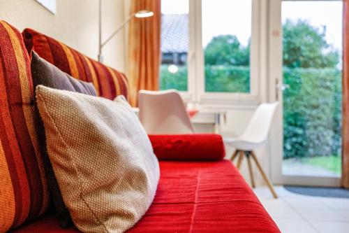 a red couch with pillows on it with a window at Bungalow Westerland Kampstrasse in Westerland
