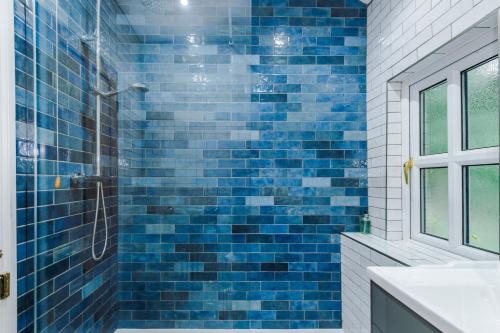 a blue tiled bathroom with a shower and a sink at Fisherman's Cottage in Chester