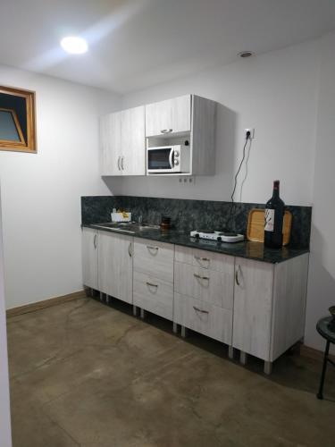 a kitchen with white cabinets and a black counter top at Alojamiento Gofioplaya in Arinaga