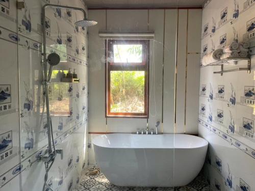 a white bath tub in a bathroom with a window at Melalueca tay ninh in Tây Ninh