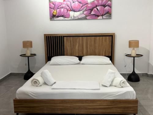 a bedroom with a bed with white sheets and towels at SunWaves Apartments in Keramoti