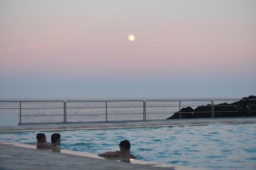 a group of people in a swimming pool near the ocean at Casa do Porto - Santa Cruz B&B in Ribeiras