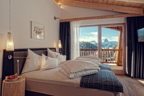 a bedroom with a bed with a view of a balcony at Alpine Hotel Gran Foda' in San Vigilio Di Marebbe