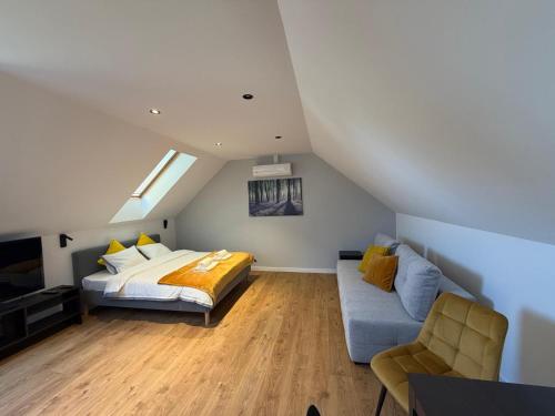 a attic bedroom with a bed and a couch at Biała Stodoła in Płoskie