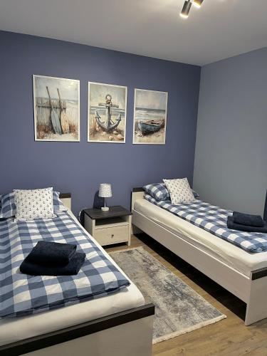 two beds in a room with paintings on the wall at Helski Zakątek in Hel