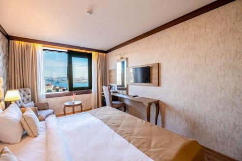 ein Hotelzimmer mit Bett, Schreibtisch und Fernseher in der Unterkunft Marble Hotel in Istanbul