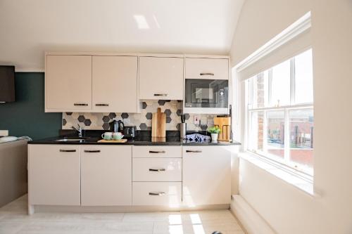 a kitchen with white cabinets and a window at Dublin Central Suites in Dublin