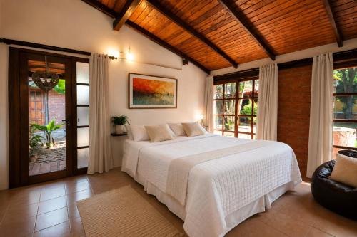 a bedroom with a large white bed and windows at La Locanda Art & Taste Retreat in Puerto Iguazú