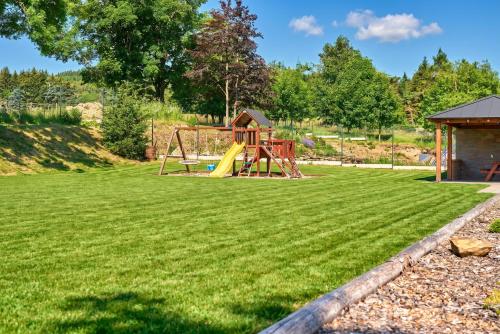 a playground with a slide on a grass field at Rezidence George by Mountain ways in Kovářská
