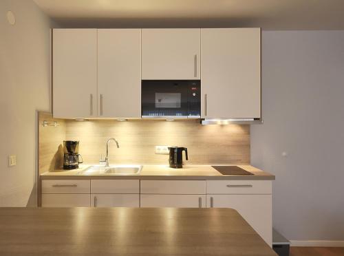 a kitchen with white cabinets and a sink at Düne, App 9 in Duhnen