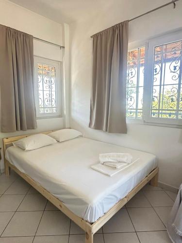 a white bed in a room with two windows at Casa Limoni in Preveza