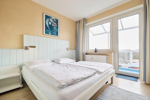 a white bed in a room with a window at Haus Schildt, FeWo 6 in Duhnen