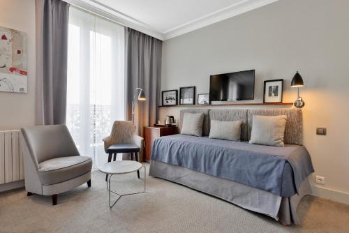 a bedroom with a bed and a chair and a television at Hôtel Londres et New York - Teritoria in Paris