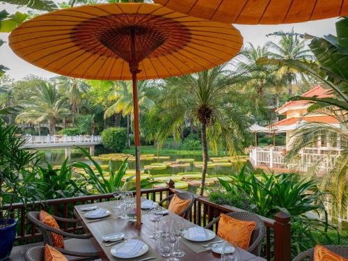 a table with chairs and umbrellas on a patio at Sofitel Angkor Phokeethra Golf & Spa Resort in Siem Reap