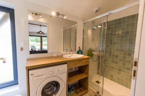 ein Badezimmer mit Waschmaschine und Waschbecken in der Unterkunft Gîte du caché in Labrit