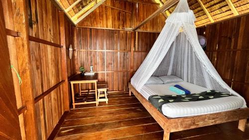a bedroom with a hammock in a wooden cabin at Nyanse Homestay - Raja Ampat in Besir