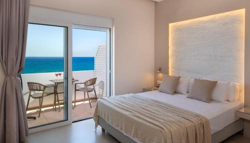 a bedroom with a bed and a balcony with the ocean at Petra Studios in Palaiochora