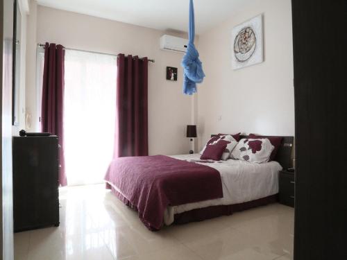 Apartment 25B11 Mixta في داكار: غرفة نوم مع سرير مع ملاءات أرجوانية ونافذة