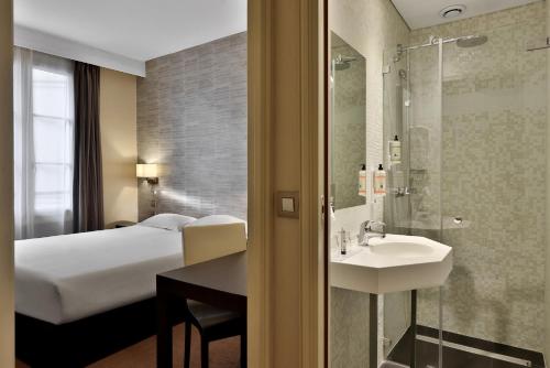 a hotel room with a bed and a sink at Hôtel Londres et New York - Teritoria in Paris