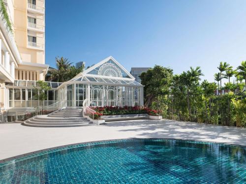 a swimming pool in front of a building with a house at Sofitel Phnom Penh Phokeethra in Phnom Penh