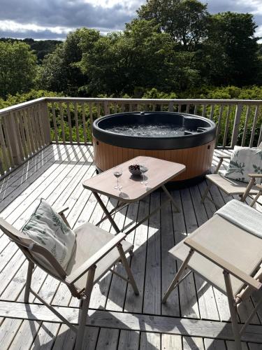 a deck with a fire pit and two chairs at Byrnside Lodge & NEW HOT TUB in Latheron