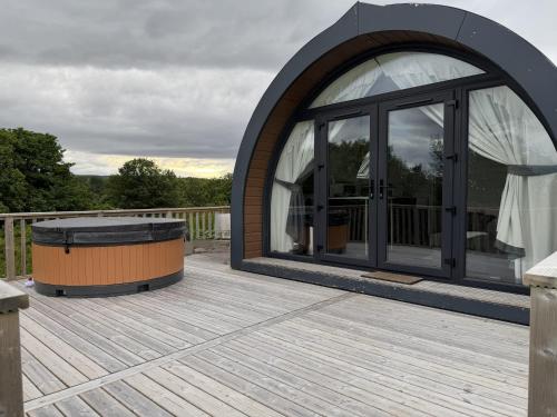 a circular building with a large window on a deck at Byrnside Lodge & NEW HOT TUB in Latheron
