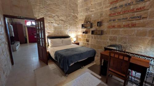 a bedroom with a bed in a stone wall at Historical Apartment in Bormla in Cospicua