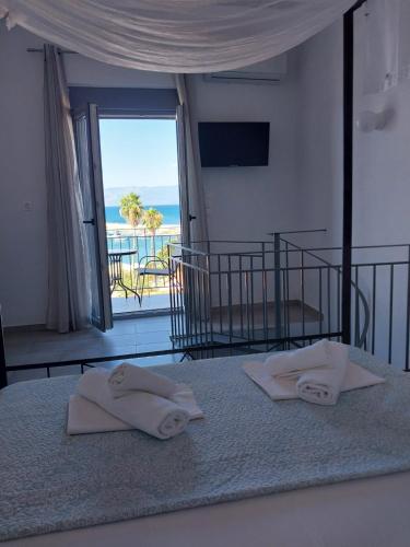 two towels on a bed with a view of the ocean at ANGIRA - Koroni Apartments in Koroni