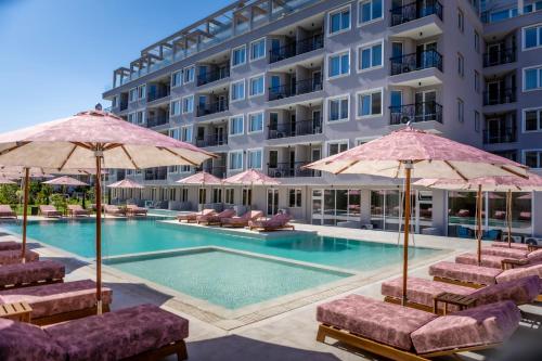 a hotel with a swimming pool with chairs and umbrellas at JADORE Deluxe Studios in Sunny Beach