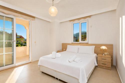a white bedroom with a bed and a balcony at Villa Kubra in Dalyan