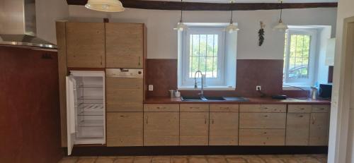 a kitchen with wooden cabinets and a sink and windows at La Maison Bleue - Escale en Ubaye in Saint-Pons
