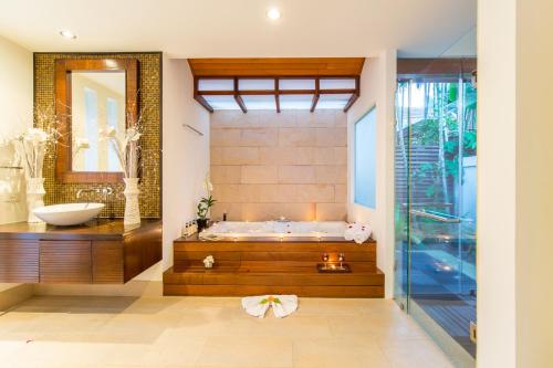 a bathroom with a tub and a sink at Dhevatara Residence Beachfront Villas in Mae Nam