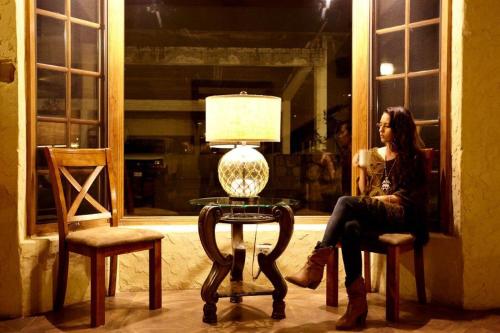 a woman sitting on a chair next to a table at Hotel Quinta Mision in Creel
