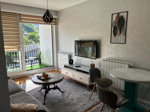 a living room with a television and a table and chairs at CENTRAL POINT APARTMENT - City centar Zenica- in Zenica