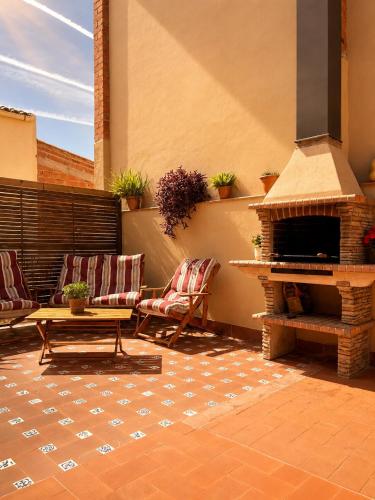 a patio with a fireplace and two chairs and a table at La Cantera in Corbera