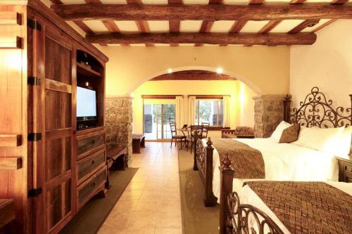 a bedroom with two beds and a flat screen tv at Hotel Quinta Mision in Creel