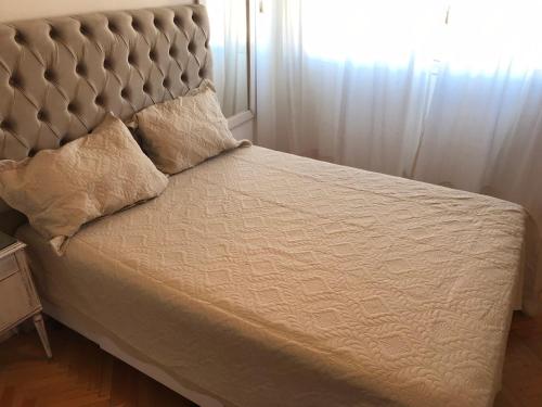 a bed with a large headboard and a window at Corrientes Center in Buenos Aires