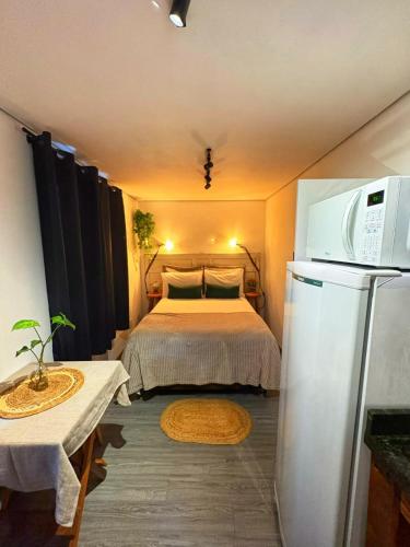 a small room with a bed and a refrigerator at Tiny House Passaúna - Climatizado, parque e deck in Curitiba