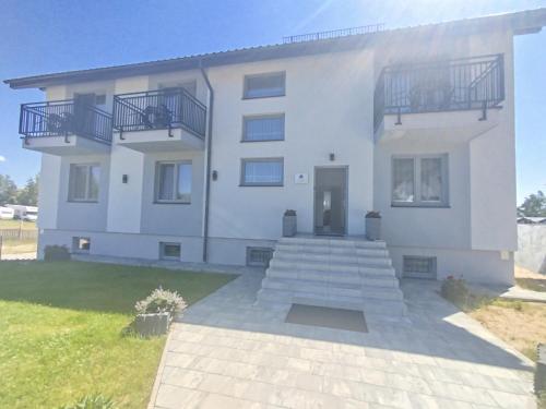 a large white house with stairs in front of it at Sosnowe Zacisze - Pokoje Gościnne Blisko Jeziora in Swornegacie
