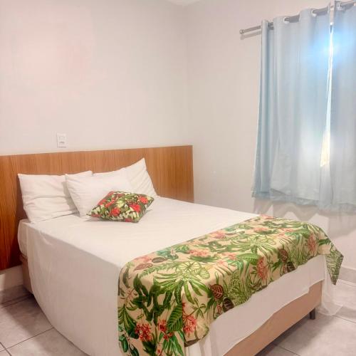 a bedroom with a bed with white sheets and a window at Hotel Coutinho in Pirapora