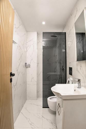 a white bathroom with a sink and a toilet at Villa Osmani in Shkodër