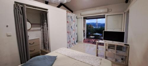 a bedroom with a bed and a television and a balcony at Kaz l'Oranger in Saint Esprit