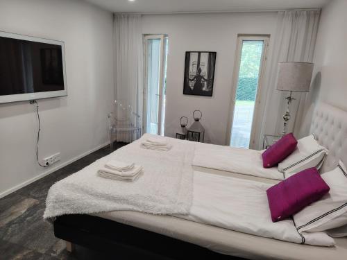 a white bedroom with a large bed with purple pillows at Anne House in Raisio
