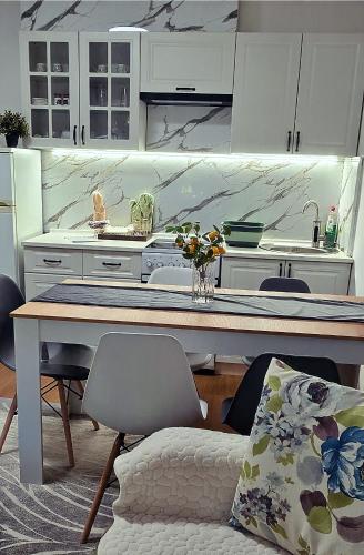 a kitchen with white cabinets and a table with chairs at G - Apartments in Kumanovo