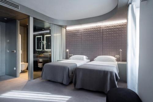 a bedroom with two beds and a bathroom at Vander Urbani Resort - a Member of Design Hotels in Ljubljana