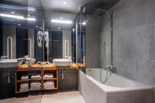 a bathroom with a tub and two sinks and a bath tub at Vander Urbani Resort - a Member of Design Hotels in Ljubljana